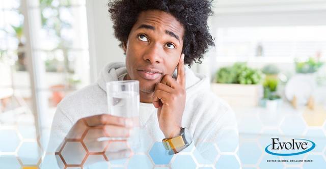 man holding glass of water thinking